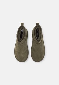 Olive green suede ankle boots with soft lining, pull tab at the back, and contrasting sole. Smooth texture with a minimal design.