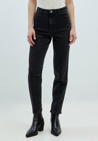 Hochtaillierte schwarze Denim-Jeans mit schlankem Schnitt, mit Fronttaschen, Knopfverschluss und geradem Bein. Strukturierter Stoff.
