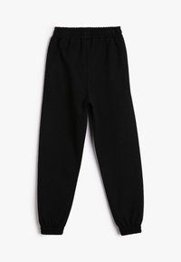 Pantalones jogger de forro polar negro con cintura elástica y puños en los tobillos, exhibidos en plano sobre un fondo blanco.