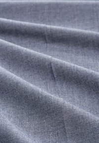 Textielstof in een middelblauwe kleur, met een gladde textuur en subtiele diagonale weefpatronen en gevouwen kreuken.