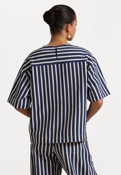 Navy and cream striped short-sleeve top with a back slit detail, featuring a relaxed fit and textured fabric. Paired with matching pants.