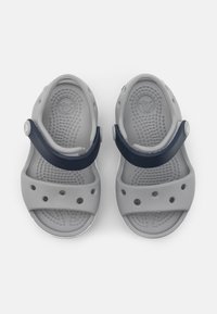 Grå sandaler med en tekstureret overflade og marineblå stropper, der har ventilationshuller, formet fodseng og cirkulære logo-detaljer.