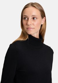 Fekete garbó pulóver puha kötött anyagból. Bordás gallérral és testhezálló hosszú ujjakkal rendelkezik. Sima textúrájú, klasszikus dizájnnal.