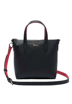 Sac à main en cuir noir texturé avec deux poignées, bandoulière réglable rouge et noire, et logo crocodile argenté sur le devant.