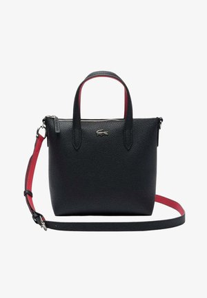 Sac à main en cuir noir texturé avec deux poignées, bandoulière réglable rouge et noire, et logo crocodile argenté sur le devant.