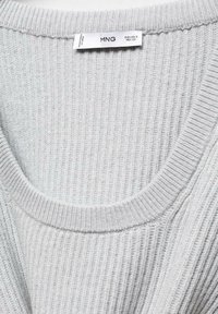 Světle šedý žebrovaný svetr s širokým výstřihem a texturovanou tkaninou. Na etiketě je uvedená značka "MNG" a velikost.