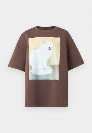 T-shirt oversized marron en coton, avec un graphique de chat blanc sur fond jaune et du texte en dessous. Manches courtes et col rond.