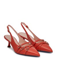 Tacchi slingback in pelle rossa con punta affilata, caratterizzati da cinturini incrociati e fibbie metalliche. Tacco a stiletto basso con un accento nero.