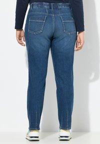 Jeans de mezclilla azul claro con una cintura elástica, cinco bolsillos y un diseño de pierna recta. La tela tiene una textura suave.