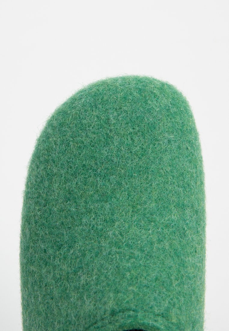 Pantofola verde in feltro con punta arrotondata e texture morbida. La parte superiore è senza cuciture, offrendo un aspetto liscio. Design minimalista.