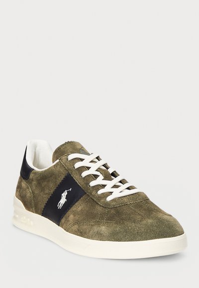Baskets en daim vert avec lacets blancs, accents bleu marine, logo brodé sur le côté et surface texturée ; semelle en caoutchouc avec légère élévation.