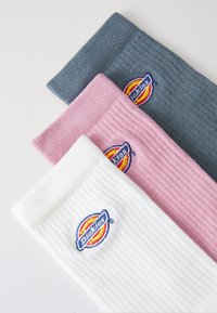 Tre paia di calzini a coste di colore bianco, rosa e grigio, con il logo multicolore di Dickies ricamato su ciascuno.
