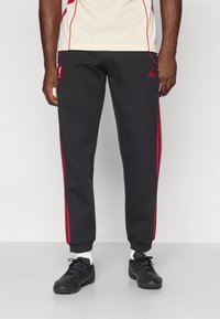 Jogginghosen aus dunkelgrauem Material mit roten Seitenstreifen, tailliertem Schnitt, elastischen Bündchen und besticktem Logo-Detail auf der Vorderseite.