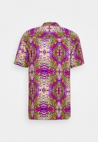 Kortærmet skjorte med et dristigt, symmetrisk farverigt dyremønster i lilla, grønne, gule og pink nuancer på en lys baggrund.