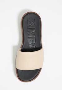 Heled beez sandal, mille laiusega rihm, must pehme tallaga ja pruun puidust tallaga. Brändinimi "BIMBA" on reljeefne.