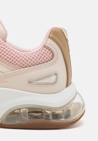 La sneaker presenta una toma superiore in mesh rosa, accenti in pelle beige, ammortizzazione d'aria nella suola e una suola in gomma traslucida. Logo del marchio visibile.