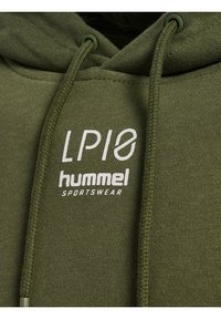 Kaptur w oliwkowo-zielonym kolorze wykonany z teksturowanej tkaniny, z kieszenią kangurka i sznurkami. Biały logotyp z napisami "LP10" i "hummel SPORTSWEAR".