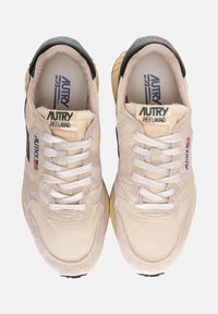 Sneaker beige e nere con tomaia in suede e rete texturizzati, lacci bianchi piatti, colletto imbottito e suola in gomma leggera.