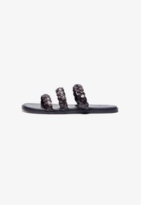 Black flat sandals featuring three braided straps, a smooth matte finish, and a low-profile sole for comfort and ease of wear.