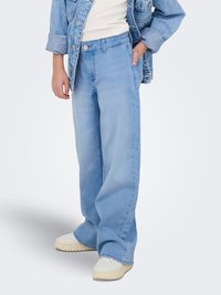 Vaqueros de pierna ancha en color azul claro, de material denim, con cierre de botones, bolsillos delanteros y detalles de costuras en contraste. Combinados con zapatillas blancas.