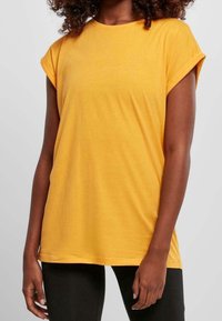 Lyhythihainen keltainen t-paita, joka on valmistettu pehmeästä puuvillasta. Paidassa on pyöreä kaula-aukko, käännetyt hihat ja rento istuvuus sekä sileä pinta.