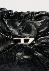 Sort læderclutch med struktureret indsamling og en fremtrædende sølvfarvet hardware lukning med geometrisk design.