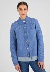 Cardigan blu lavorato a maglia con una texture a costine, caratterizzato da motivi a treccia sulle maniche e quattro grandi bottoni sul davanti.