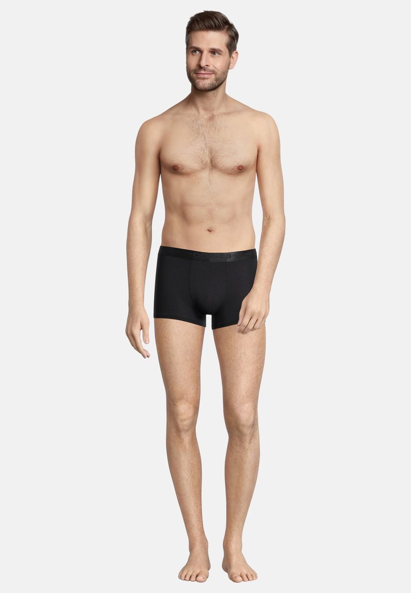 Boxer shorts neri realizzati in tessuto elasticizzato, con un tascone sagomato e una morbida cintura elastica, indossati da un modello con pelle nuda.