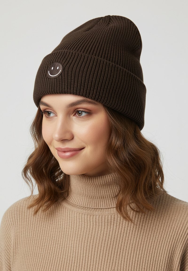 Brown ribbed knit beanie featuring a circular white smiley face patch. Soft texture with a snug fit, ideal for cold weather.