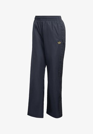 Pantaloni da tuta blu navy realizzati in materiale leggero, con cinturino elastico in vita e dettagli a tre strisce lungo i lati. Logo dorato.