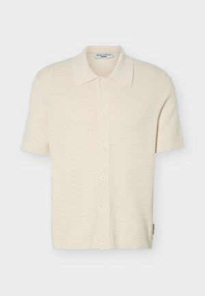 Short-sleeve cream knit cardigan with textured pattern, button front, and classic collar, displayed on plain background.