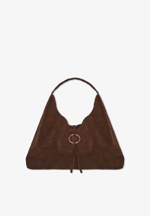 Sac bandoulière en daim marron de forme triangulaire, avec un accent circulaire doré au centre et un détail de fermeture nouée. Texture lisse.