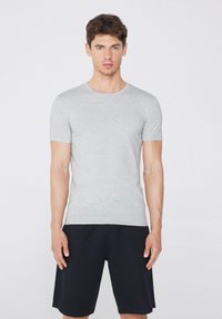 Camiseta gris de manga corta hecha de una tela suave, con un escote redondo. Combinada con pantalones cortos negros, que muestran un diseño y ajuste simples.