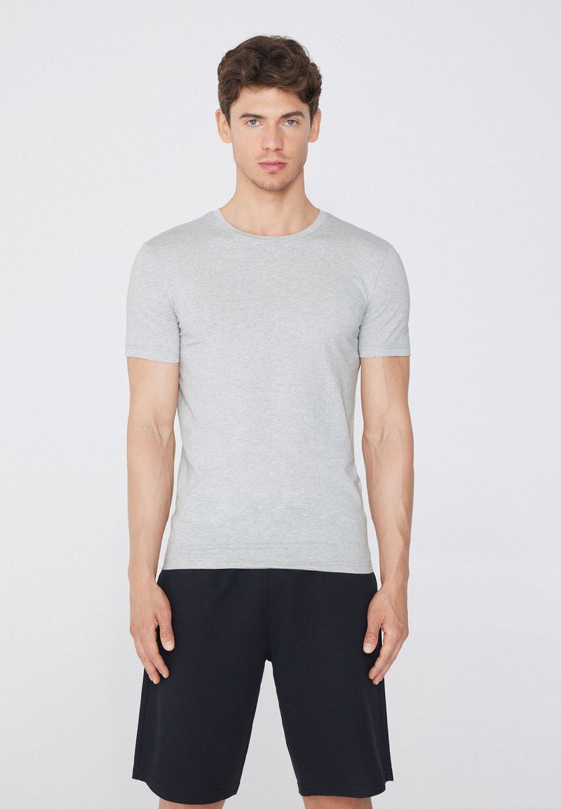 Camiseta gris de manga corta hecha de una tela suave, con un escote redondo. Combinada con pantalones cortos negros, que muestran un diseño y ajuste simples.