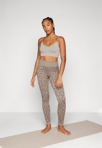 Lichtgrijze bralette en bruine legging met luipaardprint, aansluitend ontwerp, rekbare stof, verstelbare schouderbanden, zachte textuur en hoge tailleband.