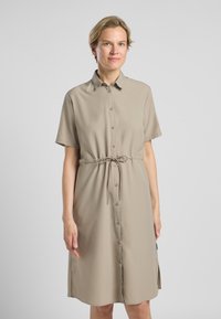 Beige knoopshirtjurk met een trekkoord in de taille, korte mouwen en een knielange zoom. Gladde textuur en minimalistisch ontwerp.