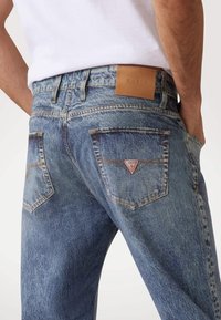 Blauwe spijkerbroeken van denim met een vervaagde wassing, voorzien van een leren logo-patch op de tailleband en een driehoekig logo op de achterzak.