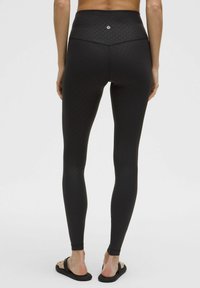 Zwarte leggings met een hoge tailleband, voorzien van een subtiel stippenpatroon. Gemaakt van rekbaar materiaal, ontworpen voor comfort en beweging.