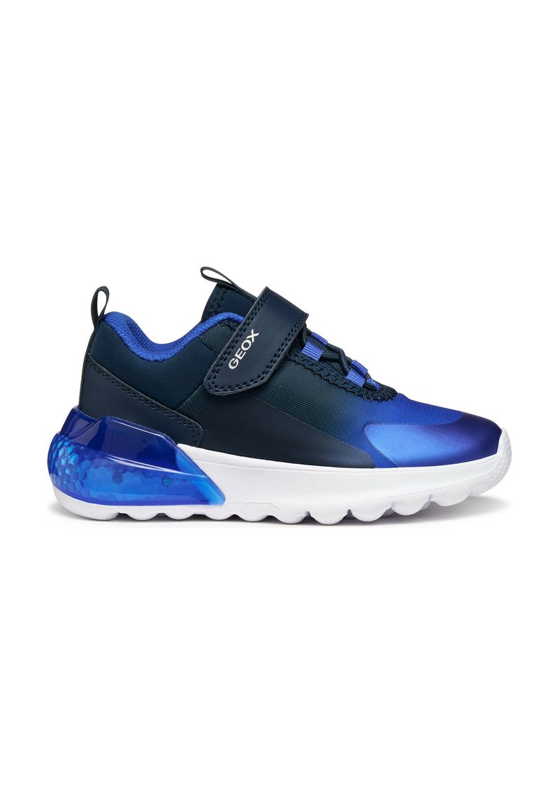 Sneakers blu navy con una superficie liscia e lucida, dotati di dettagli blu, una chiusura in velcro e una suola in gomma bianca con un tallone testurizzato.