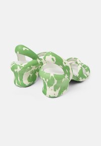 Green and white patterned platform shoes with a rounded design, featuring wide straps and an open back. Made of a flexible material.