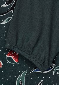 Dark green fabric with a gathered cuff detail, featuring a floral pattern in red, blue, and white on a dotted background.