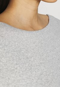 Šedý bavlněný top s kulatým výstřihem, který se vyznačuje jemnou texturou a jednoduchým designem, zaměřeným na pohodlí a minimalismus.