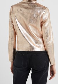 Metallisch roségoldene Kunstlederjacke mit taillierter Passform und langen Ärmeln, die sichtbare Nähte und einen cropped Saum aufweist.