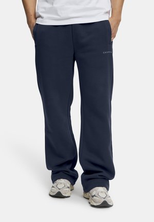 Marineblå joggingbukser i blødt materiale med sidelommer og lige ben. CASPARA-logoet i hvidt på den nederste front.