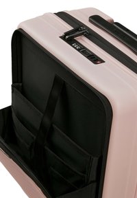 Hard-shell suitcase in soft pink with black accents. Interior features multiple pockets and organized compartments. Locking zipper mechanism visible.