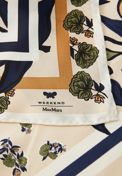 Foulard di seta con sfondo crema, impreziosito da motivi geometrici blu navy e oro, foglie verdi e dettagli floreali. L'etichetta del marchio è visibile.