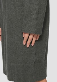 Robe-sweater gris foncé en tissu tricoté doux, dotée de poignets côtelés et d'un subtil logo près de l'ourlet.