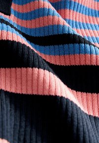Tissu de pull en tricot avec des rayures horizontales en bleu marine, noir, bleu clair et corail. La texture côtelée met en valeur le détail structurel.