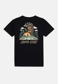 Juodas medvilninis marškinėliai su grafika, vaizduojančia lokio leteną virš stovyklavietės su medžiais ir debesis, apačioje yra tekstas "Santa Cruz".