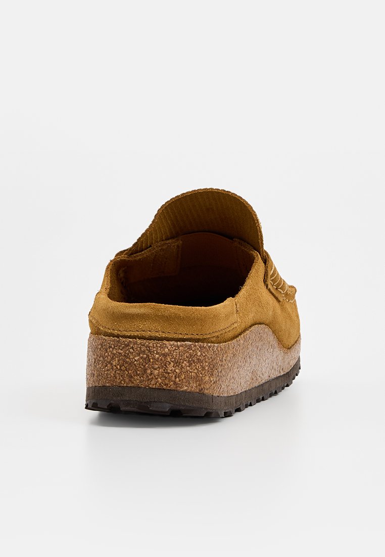 Chaussure en suede marron à enfiler avec semelle en liège épaisse et semelle en caoutchouc, vue de l'arrière sur fond blanc.